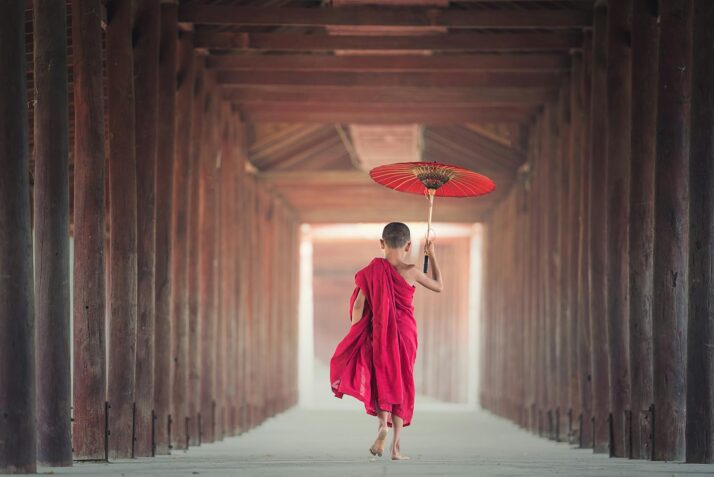 boy walking between wooden frame while holding umbrella